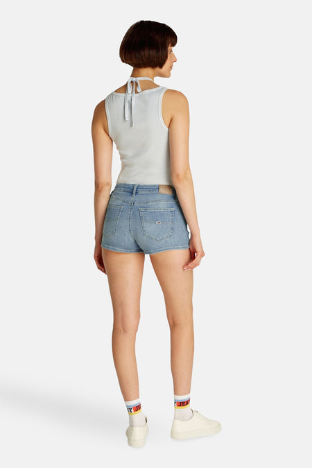 Lichtblauwe denim short van TOMMY JEANS, met korte pijpen en gedragen met witte sokken en sneakers.
