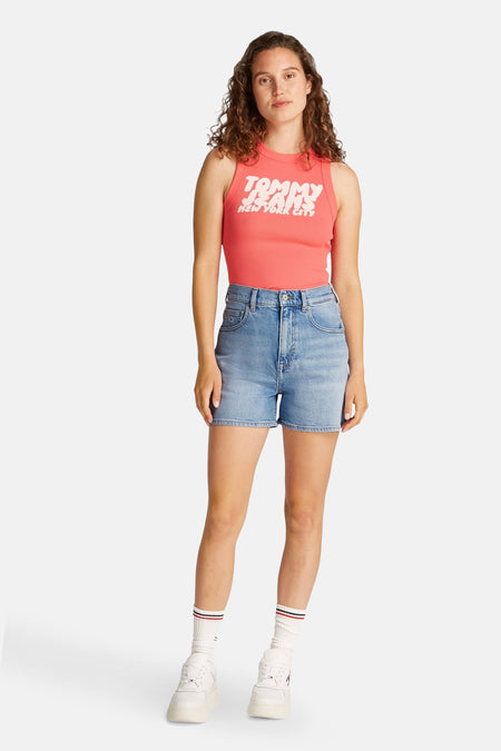 Korte lichtblauwe denim short van TOMMY JEANS, gecombineerd met een roze top en witte sneakers met sokken.
