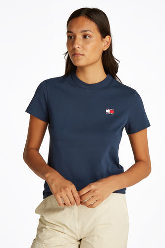 T-shirt bleu à manches courtes de TOMMY JEANS, vue arrière avec un pantalon cargo beige et des chaussures blanches.