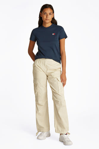 T-shirt bleu à manches courtes de TOMMY JEANS, porté avec un pantalon cargo beige et des baskets blanches.