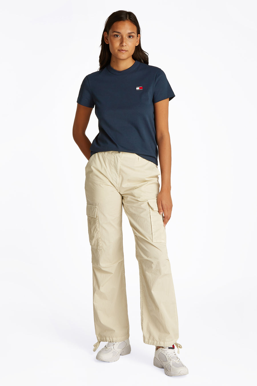 T-shirt bleu à manches courtes de TOMMY JEANS, porté avec un pantalon cargo beige et des baskets blanches.
