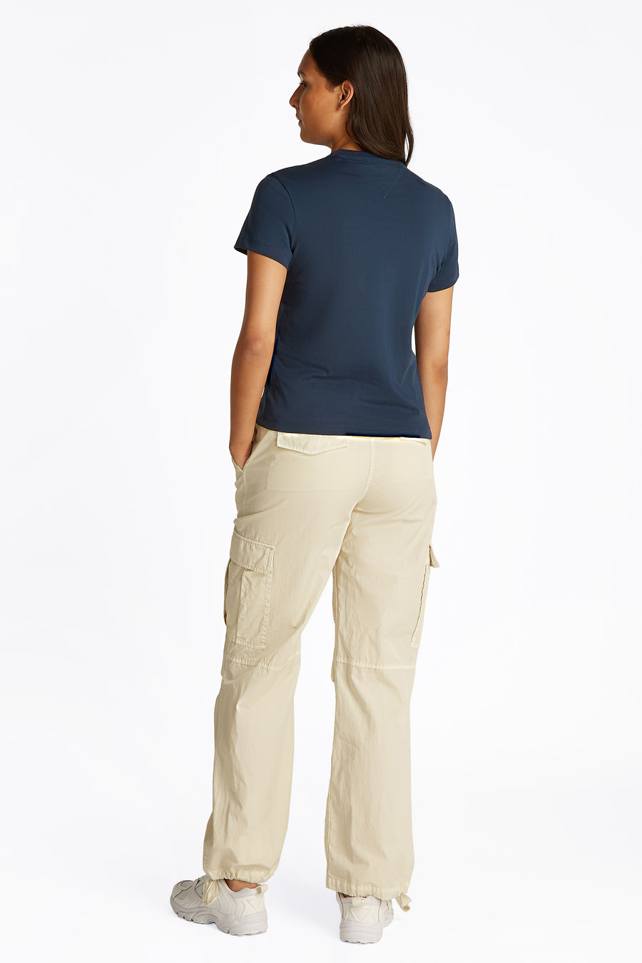 Blauw T-shirt met korte mouwen van TOMMY JEANS, rugaanzicht met beige cargo broek en witte schoenen.
