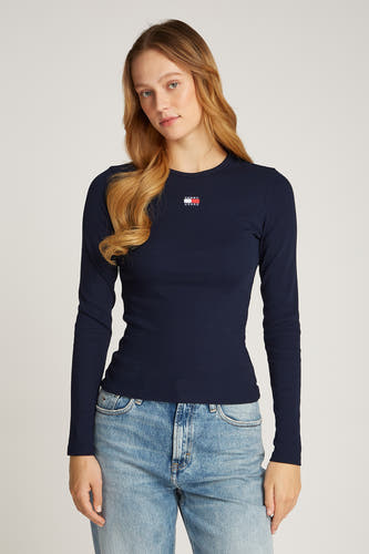 Donkerblauwe longsleeve T-shirt van TOMMY JEANS, met een ribgebreide textuur en een logo op de borst, gedragen met een blauwe spijkerbroek.
