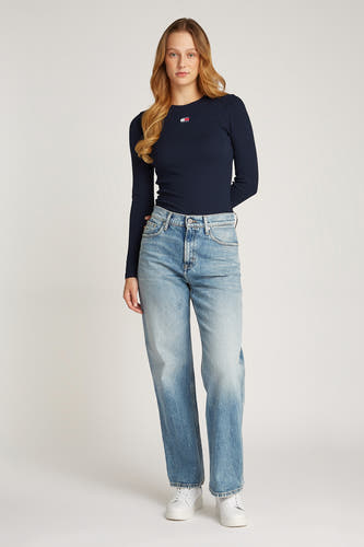 Blauw T-shirt met lange mouwen van TOMMY JEANS, met een klein logo op de borst, gecombineerd met blauwe jeans en witte sneakers.