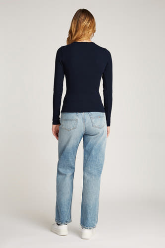 Blauw shirt met lange mouwen van TOMMY JEANS, gedragen met lichtblauwe jeans en witte sneakers.
