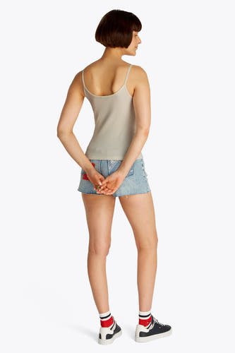 Ecrukleurige singlet van TOMMY JEANS, gedragen met een denim short en gestreepte sokken, van achteren gezien.
