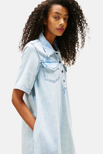 Lichtblauwe denim jurk met korte mouwen van TOMMY JEANS, met borstzak en knoopsluiting, in zijaanzicht.