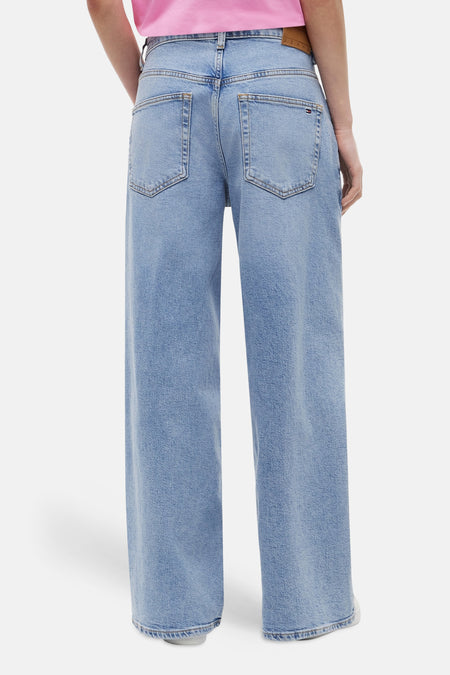 Jeans larges en denim bleu clair de TOMMY JEANS, avec poches arrière et une étiquette en cuir marron.