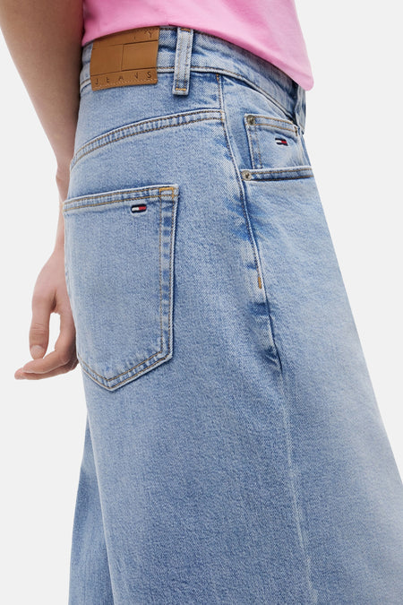 Jeans en denim bleu clair ample de TOMMY JEANS, avec poches arrière et une étiquette de marque marron à la ceinture.
