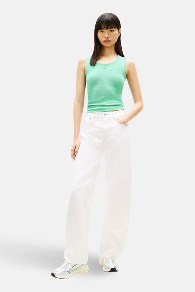 Groen T-shirt met korte mouwen van TOMMY JEANS, gedragen met witte broek en kleurrijke sneakers.