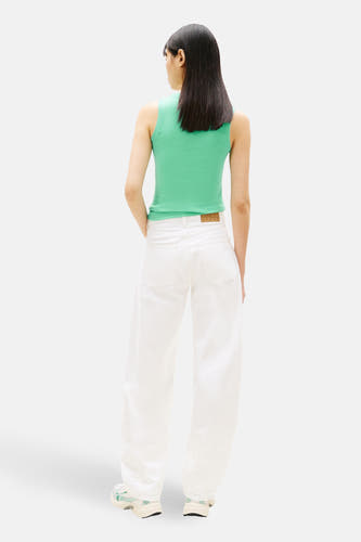 Groen T-shirt met korte mouwen van TOMMY JEANS, gezien van achteren, gecombineerd met een witte broek en sneakers.