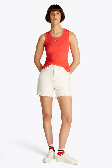 T-shirt orange à manches courtes de TOMMY JEANS, porté avec un short en denim blanc et des baskets basses avec des chaussettes.