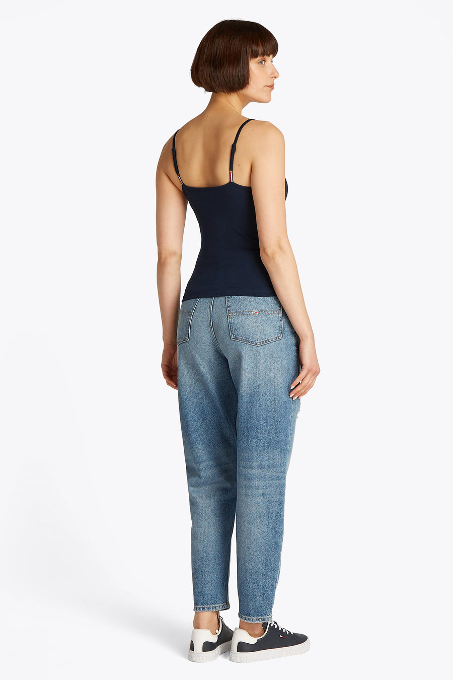 Blauwe singlet van TOMMY JEANS, met spaghettibandjes, gecombineerd met een jeans en sneakers.
