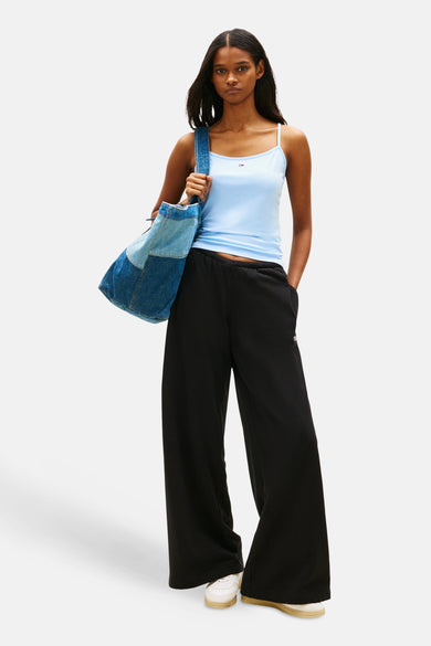Blauwe tanktop van TOMMY JEANS, met dunne bandjes, gecombineerd met een denim tas en zwarte broek.