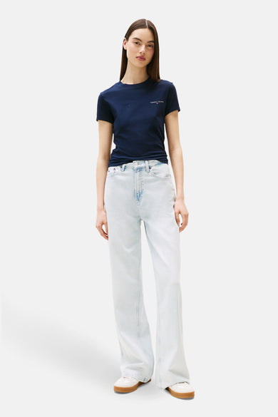 T-shirt bleu à manches courtes de TOMMY JEANS, porté avec un jean bleu clair à larges pattes et des baskets blanches.