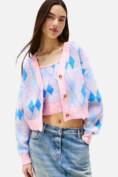 Roze cardigan van TOMMY JEANS met blauwe ruitprint, gedragen over een bijpassend topje en jeans.