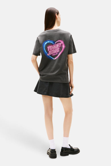 Grijs T-shirt met korte mouwen van Tommy Jeans, met hartvormige print op de achterkant, gecombineerd met een donkere rok.
