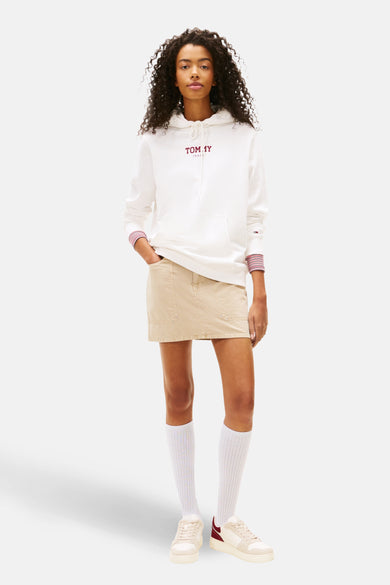 Witte sweater met kap van TOMMY JEANS, met gestreepte manchetten en gecombineerd met een beige rok, witte sokken en crèmekleurige sneakers.