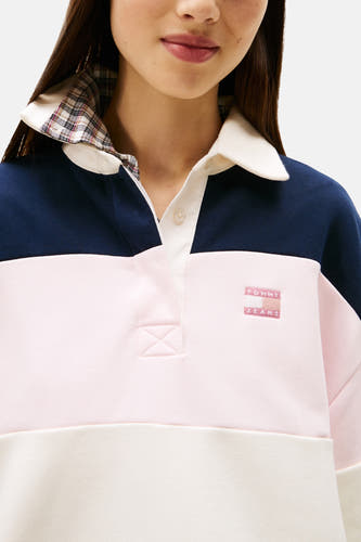 Close-up van een vrouw in een Tommy Jeans-poloshirt met marineblauw, roze en crèmekleurige blokken.