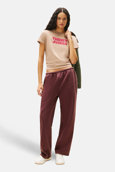 T-shirt beige à manches courtes de Tommy Jeans, avec logo rose sur la devanture et longue jogging marron.