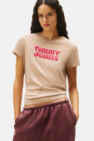 T-shirt beige à manches courtes de TOMMY JEANS, avec impression de logo rose, associé à un pantalon de jogging bordeaux.