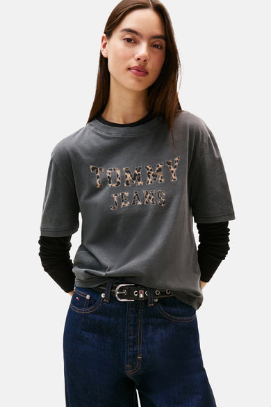 Grijs T-shirt met korte mouwen van TOMMY JEANS, met luipaardprint letters, gecombineerd met donkere jeans en een zwarte riem.