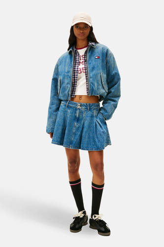 Denim jeansjas van TOMMY JEANS, met een witte top, blauw geruite blouse, denim rok, zwarte sokken en zwarte schoenen.
