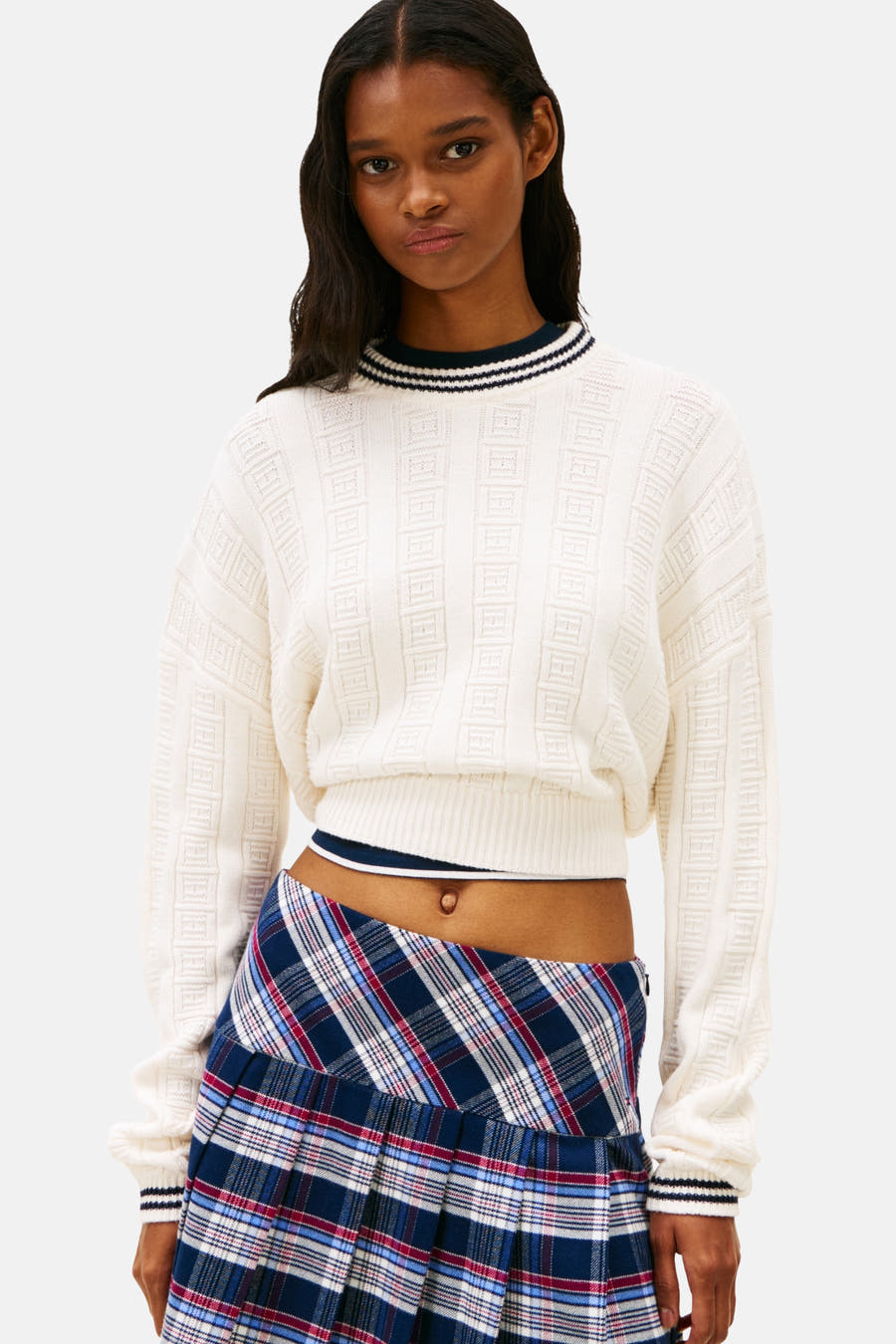 Pull-over blanc avec col rond de TOMMY JEANS, à motif côtelé et une minirobe rayée, chaussettes noires et loafers noirs.