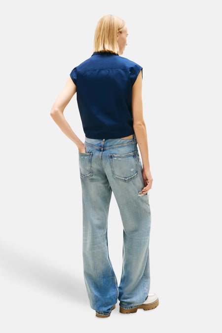 Haut sans manches bleu de TOMMY JEANS, de coupe courte et porté avec un jean.