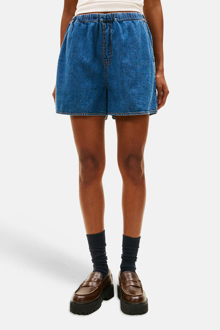 Blauwe denim short van TOMMY JEANS, met elastische tailleband, gecombineerd met sokken en leren instappers.