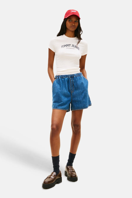 Middenblauw denim short van TOMMY JEANS, met elastische tailleband, gedragen met een wit T-shirt en rode pet.
