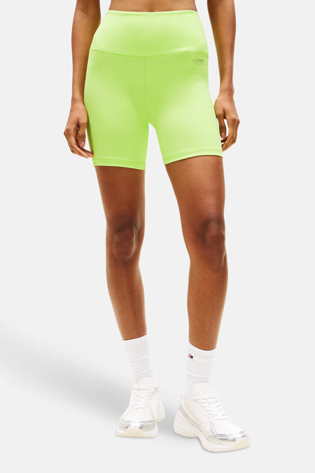 Short vert de TOMMY JEANS, combiné avec un soutien-gorge de sport assorti, des chaussettes blanches et des baskets.