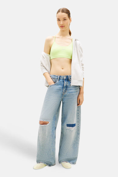 Groene korte top van TOMMY JEANS met logo, gedragen met open grijze hoodie en gescheurde jeans.