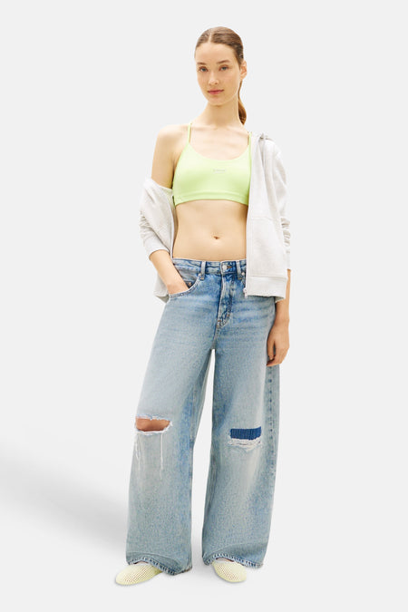 Groene korte top van TOMMY JEANS met logo, gedragen met open grijze hoodie en gescheurde jeans.
