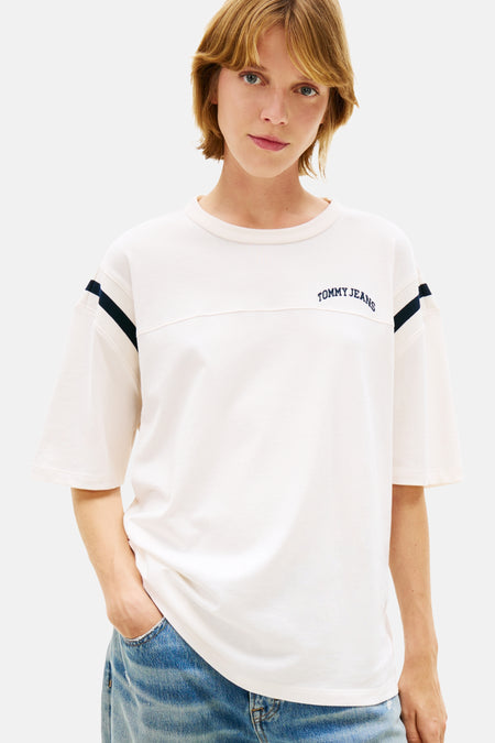 Wit T-shirt met korte mouwen van TOMMY JEANS, met donkerblauwe strepen op de schouders en een jeansbroek.