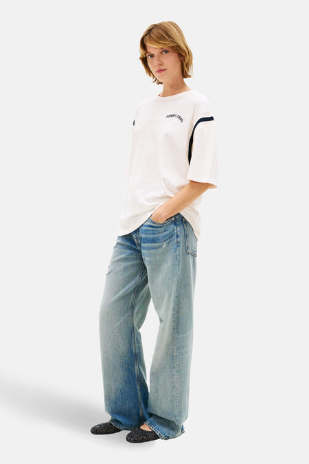 Wit T-shirt met korte mouwen van TOMMY JEANS, met donkerblauwe details op de mouwen en losse jeans.