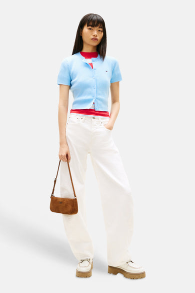 Blauw gilet van TOMMY JEANS, gedragen over een rood shirt en gecombineerd met witte broeken en bruine handtas.
