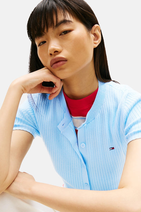 Gilet bleu de TOMMY JEANS, porté sur une chemise rouge à rayures blanches et à texture plissée.