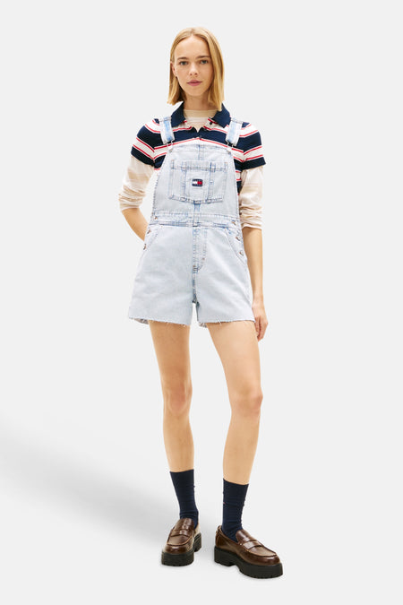 Combinaison en denim bleu clair de TOMMY JEANS, dos avec bretelles sur un t-shirt rayé.