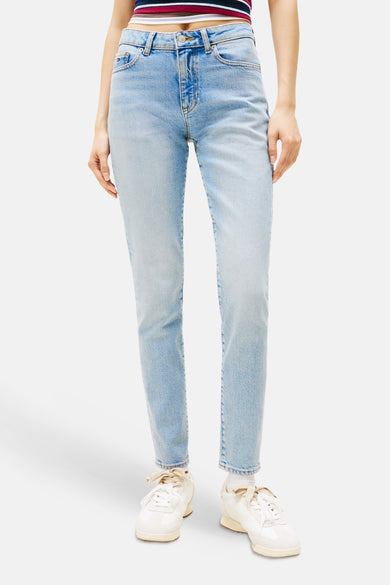 Slim jeans van lichtblauw denim van TOMMY JEANS, met witte sneakers en een gestreepte top.