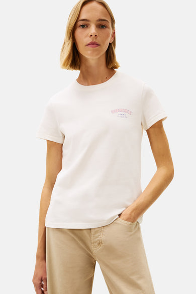 Ecru T-shirt met korte mouwen van TOMMY JEANS, met een logo-opdruk op de borst, gedragen met een beige broek.
