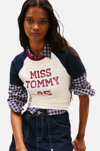 Multicolor T-shirt met korte mouwen van TOMMY JEANS, met een geruit overhemd eronder en een donkerblauwe jeans.
