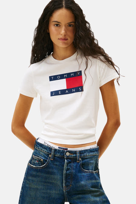 T-shirt blanc à manches courtes de TOMMY JEANS, avec logo sur la poitrine, associé à un gilet imprimé tigre et des shorts en denim.