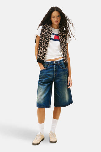 Wit T-shirt met korte mouwen van TOMMY JEANS, met logo op de borst, gecombineerd met een vest met panterprint en denim shorts.

