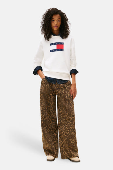 Pull-over blanc de TOMMY JEANS, avec logo sur la poitrine, porté avec un chemisier en denim et une pantalon à imprimé animal.