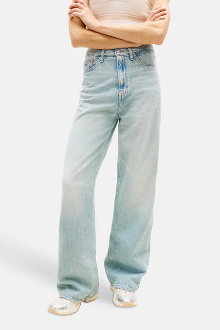 Jeans larges en denim bleu clair de Tommy Jeans, de couleur unie et à coupe ample, portées avec un polo rayé et des baskets.