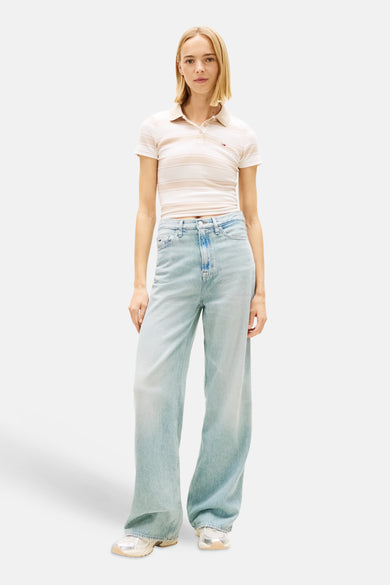 Wijde jeans van lichtblauw denim van Tommy Jeans, met een effen kleur en losse pasvorm, gedragen met een gestreept poloshirt en sneakers.