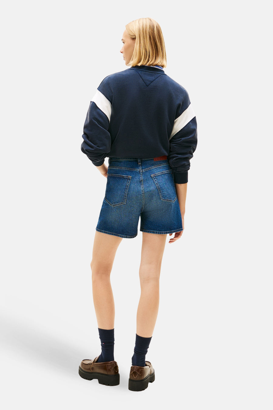 Donkerblauwe denim short van Tommy Jeans, met zakken en een rode riem, gecombineerd met een donkerblauw sweatshirt.