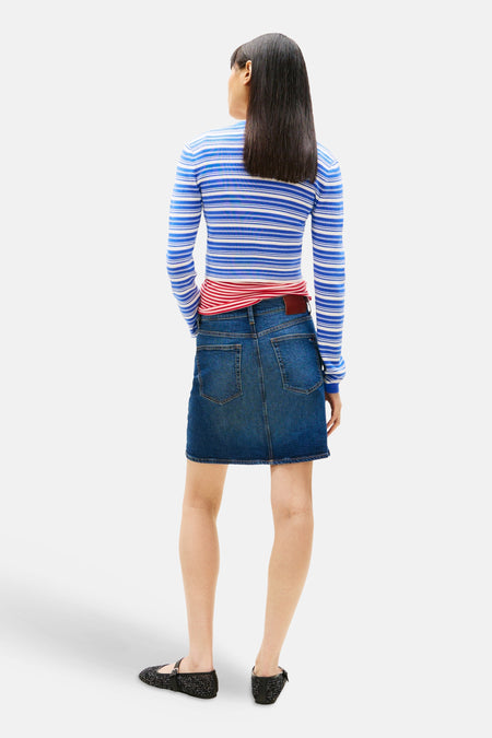 Jupe en jean bleu marine de TOMMY JEANS, avec un haut à rayures rouges et bleues et des ballerines noires.