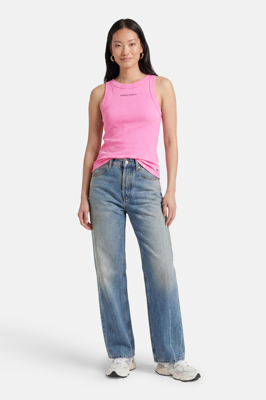 Roze ribbel tanktop van TOMMY JEANS met klein logo, gedragen met blauwe jeans en witte sneakers, front view
